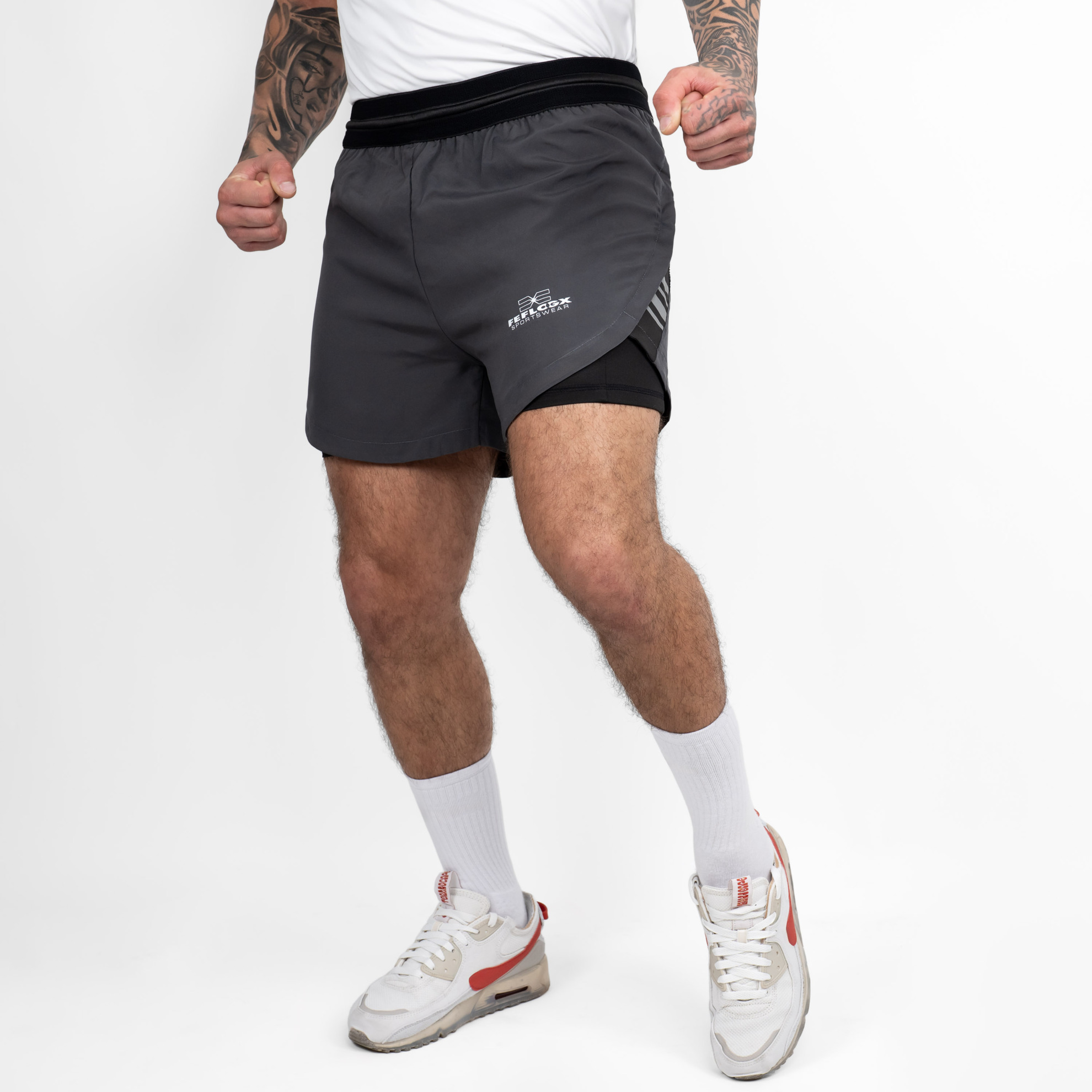 FFX 2 in 1 Performance Sport Shorts Fight Striker von FEFLOGX Sportswear, extrem hochwertige Gym Fight Shorts mit Tight Shorts, 2 in 1 Shorts, MMA Shorts, 2 in 1 Laufhose Herren, 2 in 1 Laufshorts in hellgrau, dunkelgrau & schwarz, seitliche Ansicht links vorne Action der dunkelgrauen Sportshorts. FFX 2 in 1 Performance Sport Shorts Fight Striker
