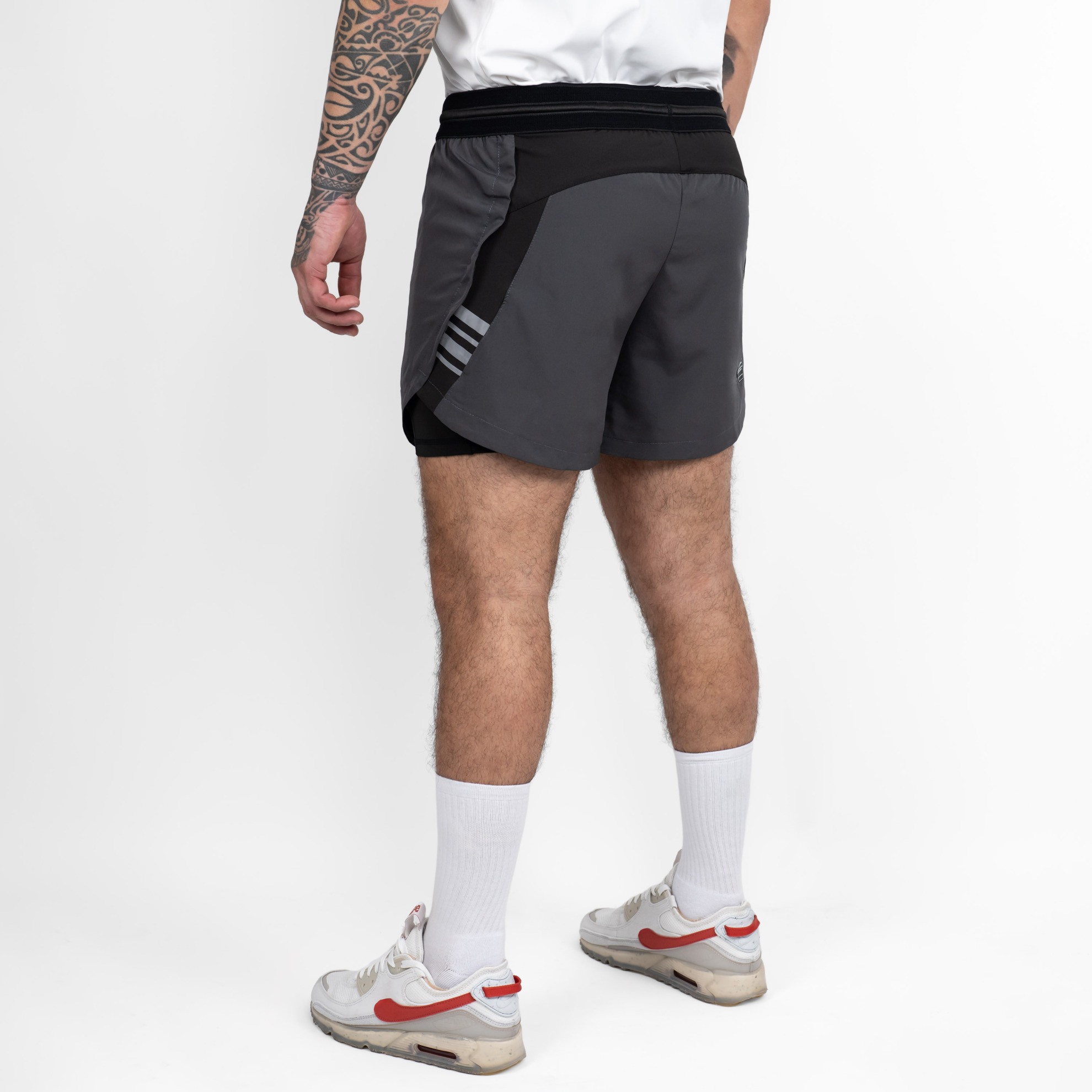 FFX 2 in 1 Performance Sport Shorts Fight Striker von FEFLOGX Sportswear, extrem hochwertige Gym Fight Shorts mit Tight Shorts, 2 in 1 Shorts, MMA Shorts, 2 in 1 Laufhose Herren, 2 in 1 Laufshorts in hellgrau, dunkelgrau & schwarz, hintere Ansicht schräg der dunkelgrauen Sportshorts. FFX 2 in 1 Performance Sport Shorts Fight Striker