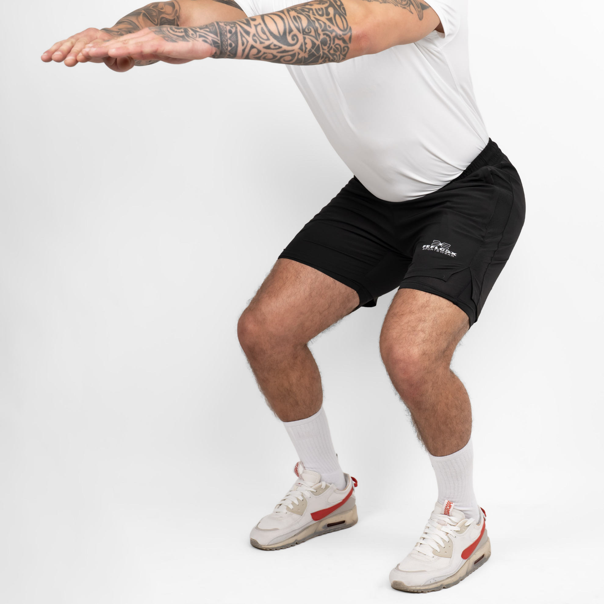FFX 2-in-1 Superior Sport Shorts mit Tights von FEFLOGX Sportswear, extrem hochwertige kurze Jogginghose, kurze Sporthose mit Tight Shorts, 2 in 1 Shorts Herren, MMA Shorts, 2 in 1 Laufhose Herren, 2 in 1 Laufshorts Herren in grau & schwarz, vordere Ansicht der schwarzen Sportshorts als Action-Bild. FFX 2-in-1 Superior Sport Shorts mit Tights