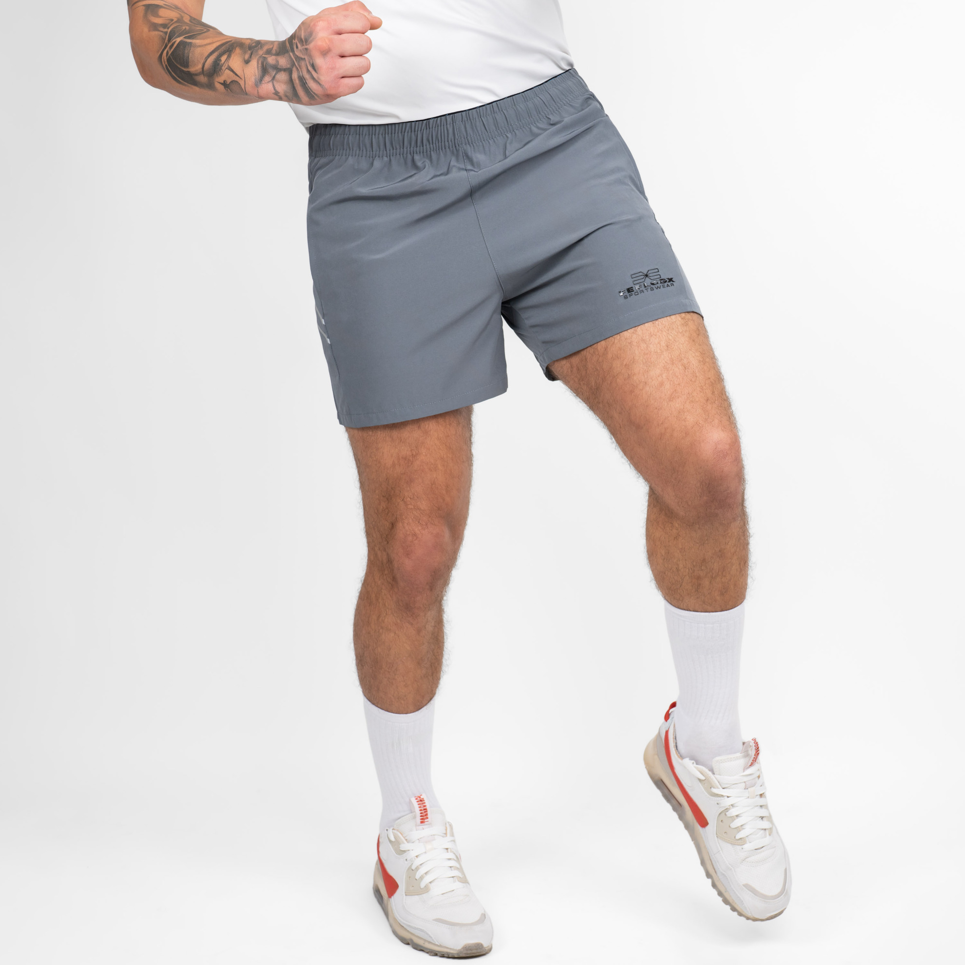 FFX Extra Kurze Sport Shorts High Power von FEFLOGX Sportswear, erstklassige Gym Shorts, super bequeme Laufshorts, Sporthose kurz Herren, kurze Jogginghose in grau & schwarz für Sport, Fitness & Kampfsport, seitliche Ansicht rechts vorne Action, graue Shorts. FFX Extra Kurze Sport Shorts High Power
