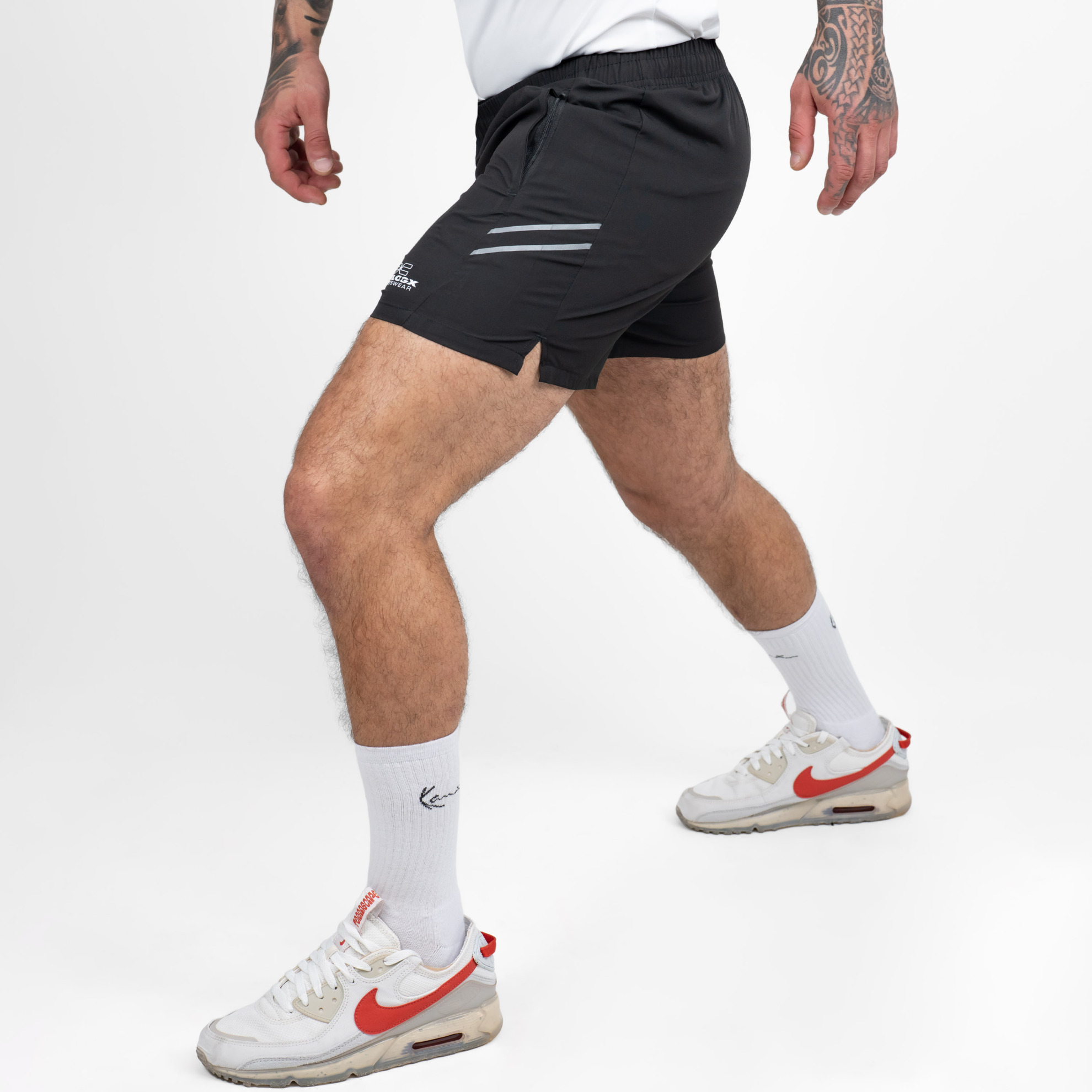 FFX Extra Kurze Sport Shorts High Power von FEFLOGX Sportswear, erstklassige Gym Shorts, super bequeme Laufshorts, Sporthose kurz Herren, kurze Jogginghose in grau & schwarz für Sport, Fitness & Kampfsport, seitliche Ansicht links vorne Action, schwarze Shorts. FFX Extra Kurze Sport Shorts High Power