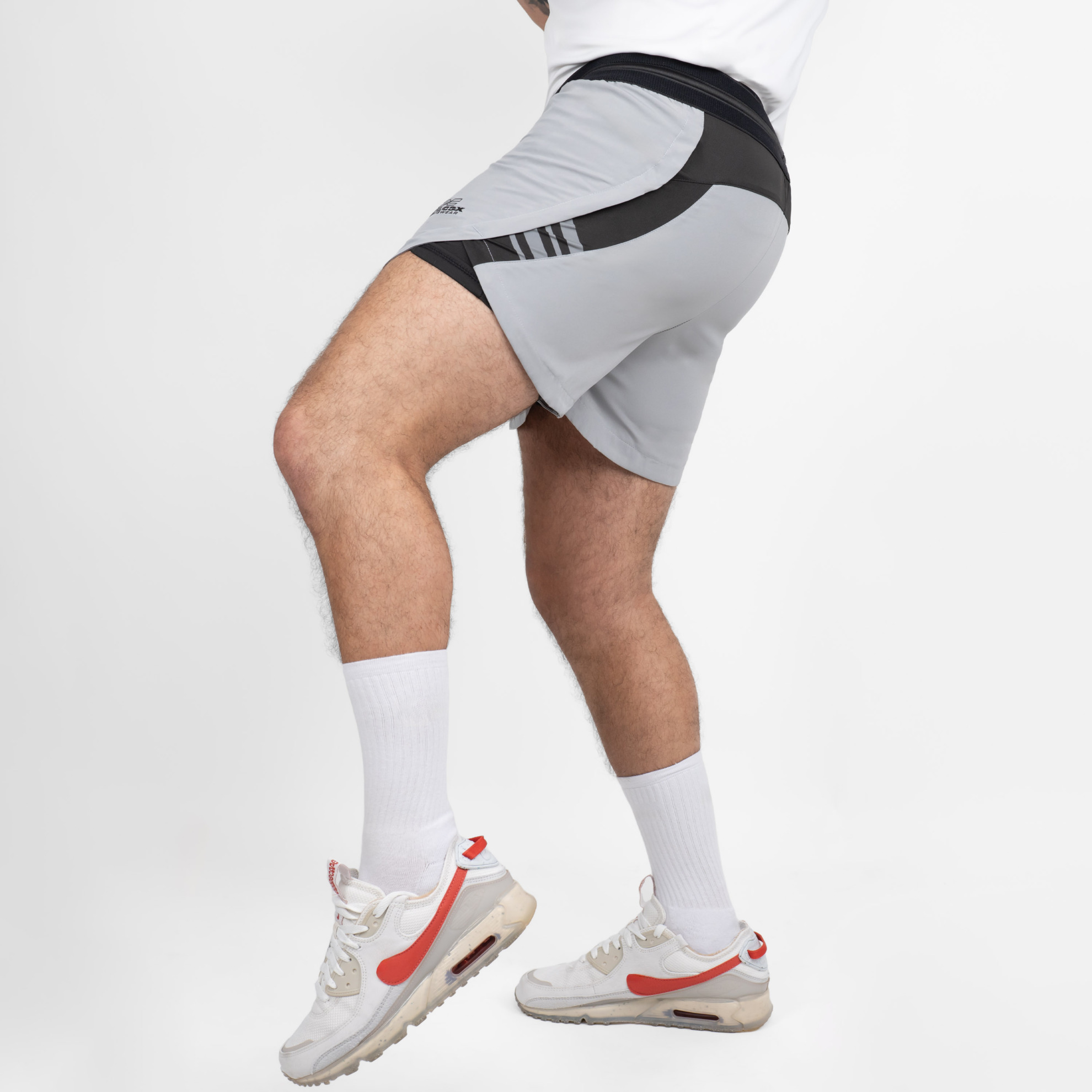 FFX 2 in 1 Performance Sport Shorts Fight Striker von FEFLOGX Sportswear, extrem hochwertige Gym Fight Shorts mit Tight Shorts, 2 in 1 Shorts, MMA Shorts, 2 in 1 Laufhose Herren, 2 in 1 Laufshorts in hellgrau, dunkelgrau & schwarz, seitliche Ansicht links vorne Action der hellgrauen Sportshorts. FFX 2 in 1 Performance Sport Shorts Fight Striker
