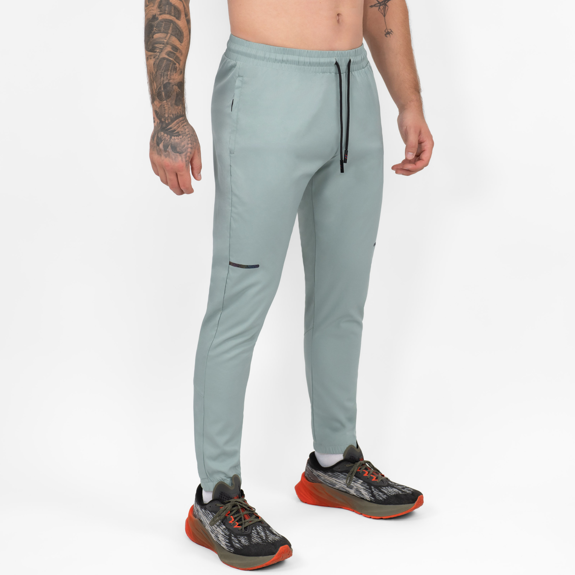 FFX Jogger Sport Hose Enduring Performance von FEFLOGX Sportswear, mit Reißverschlusstaschen, Jogginghose in schwarz, blass grün & grau, Jogginghose Herren, Sporthose, Jogging Hose, seitliche Ansicht rechts vorne der blass grünen, langen Trainingshose. FFX Jogger Sport Hose Enduring Performance